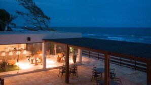 A modern building with a glass facade overlooking the ocean. - Pousada Marajuba (Ipojuca)
