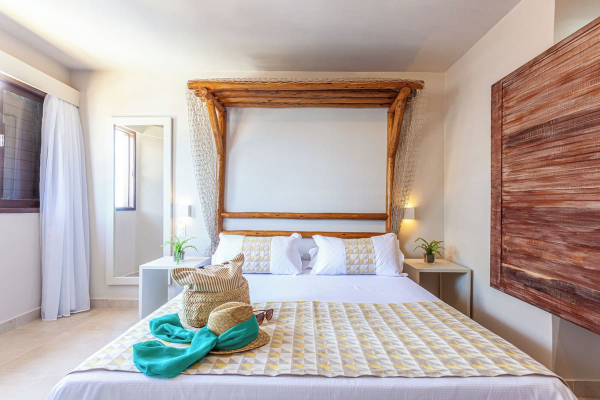 A hotel room with a large bed, a wooden headboard, and a view of the sea.