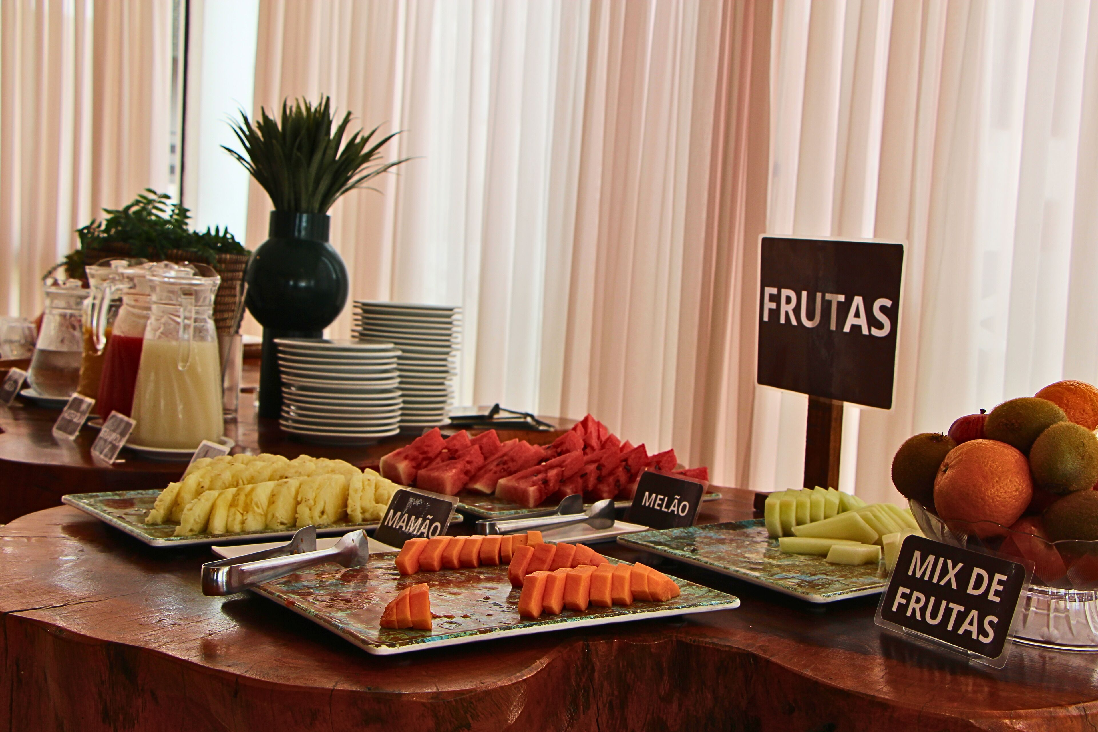A buffet with labeled fruit platters including mango, melon, and a mix of fruits.