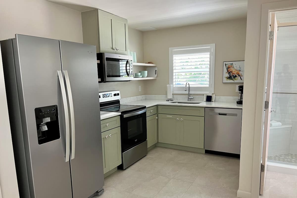 A modern kitchen with a stainless steel refrigerator, a microwave, an oven, and a dishwasher.