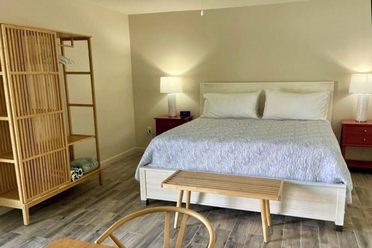 A bedroom with a bed, bedside tables, a wooden wardrobe, and a bench.