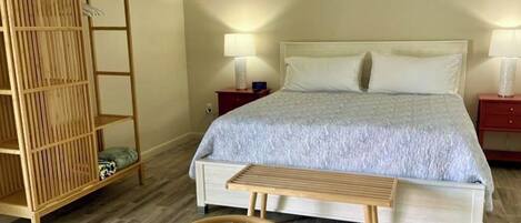 A bedroom with a bed, bedside tables, a wooden wardrobe, and a bench.