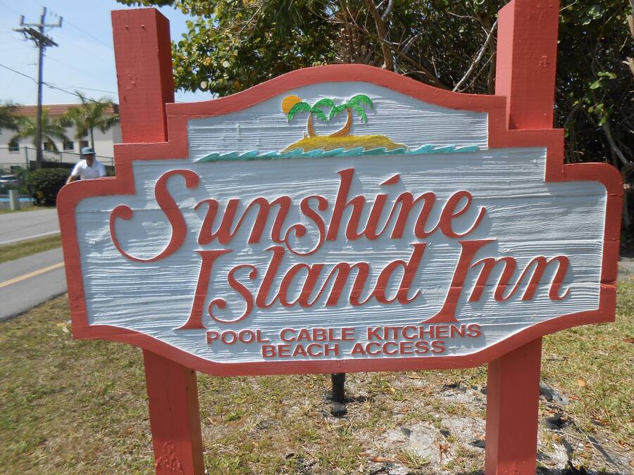 A sign for Sunshine Island Inn with a palm tree and beach scene.