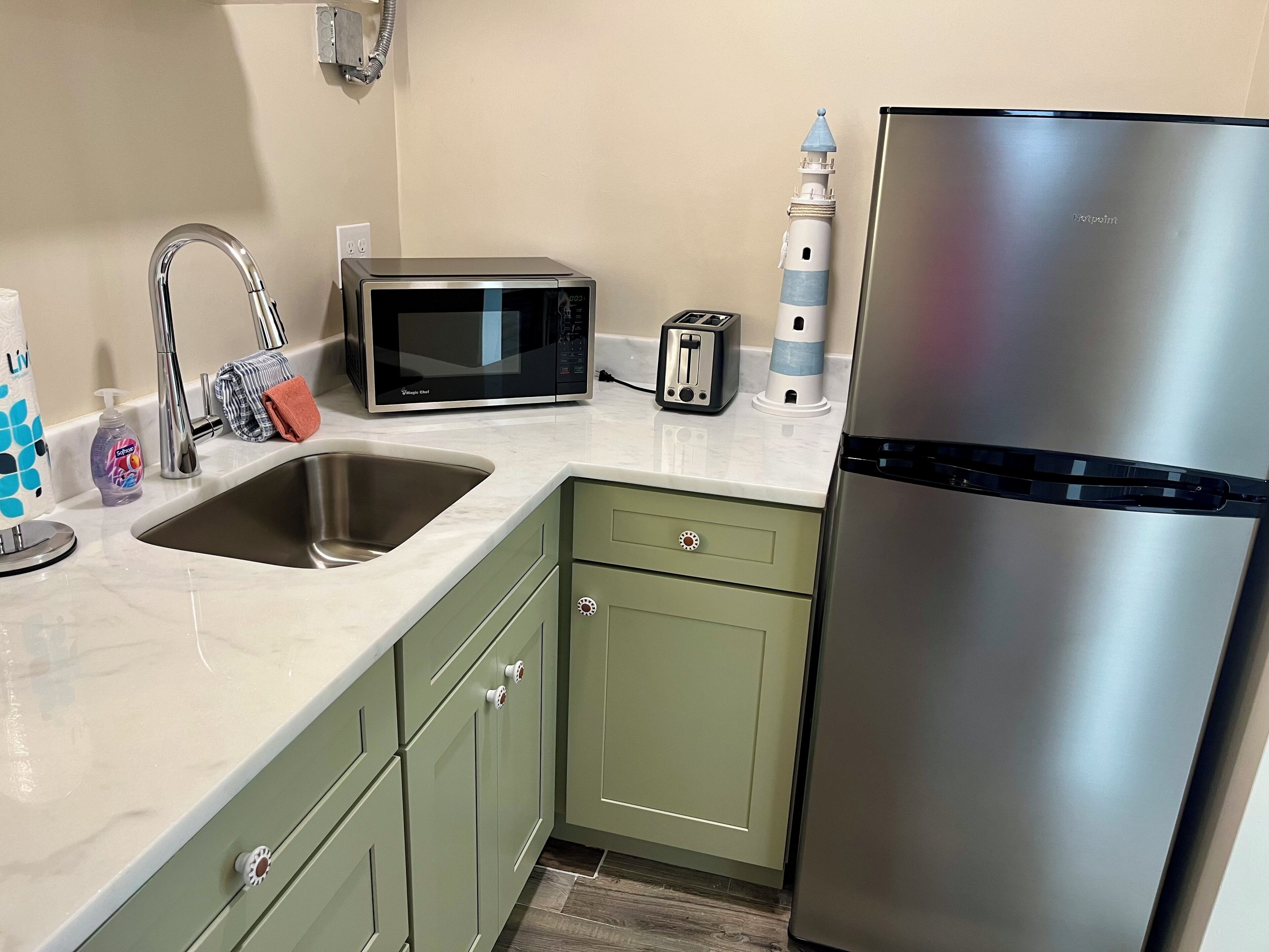 A kitchen with a stainless steel refrigerator, a microwave, a sink, and a toaster.