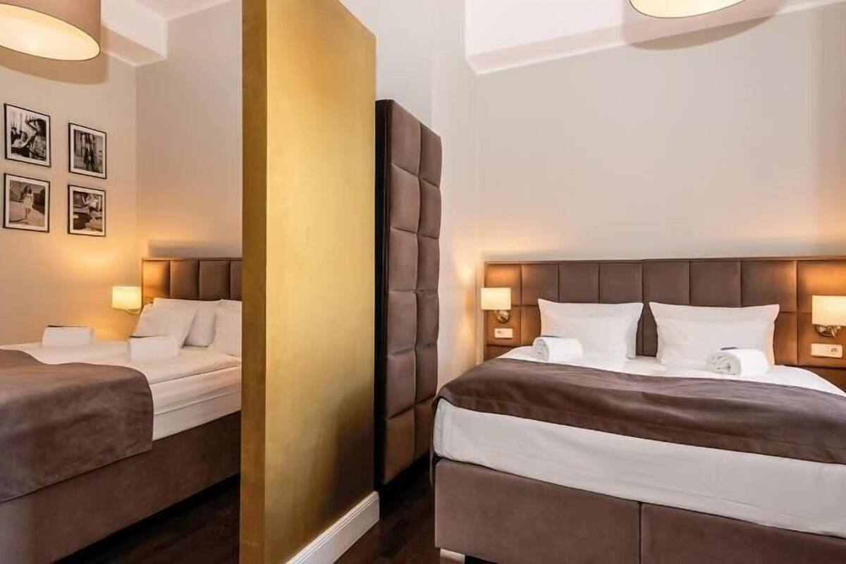 Una habitación de hotel con dos camas, cada una con cabecera y lámparas de noche.