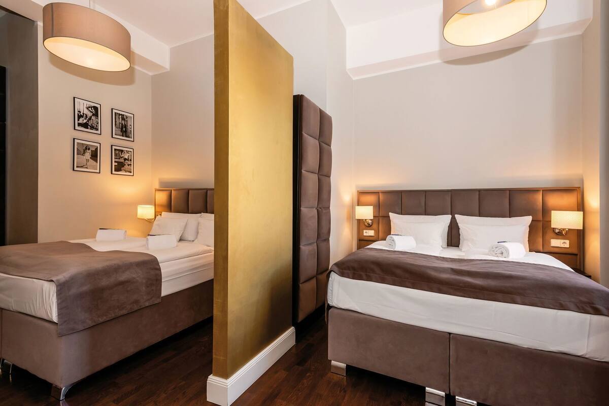 Habitación de hotel con dos camas, un pilar grande y marcos de cuadros en la pared.