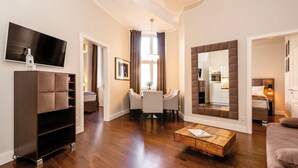 Ein modernes Wohnzimmer mit einem Flachbildfernseher, einem Holztisch und einem Essbereich mit einer Kristallleuchtre.