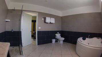 A bathroom with a bathtub, toilet, and shower area.