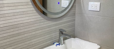 A bathroom with a white sink, a mirror, and a toilet.
