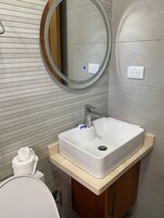Un baño con un lavabo blanco, un espejo y un inodoro.