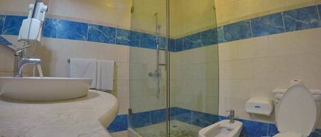 A bathroom with a glass-enclosed shower, a freestanding bathtub, a bidet, and a toilet.