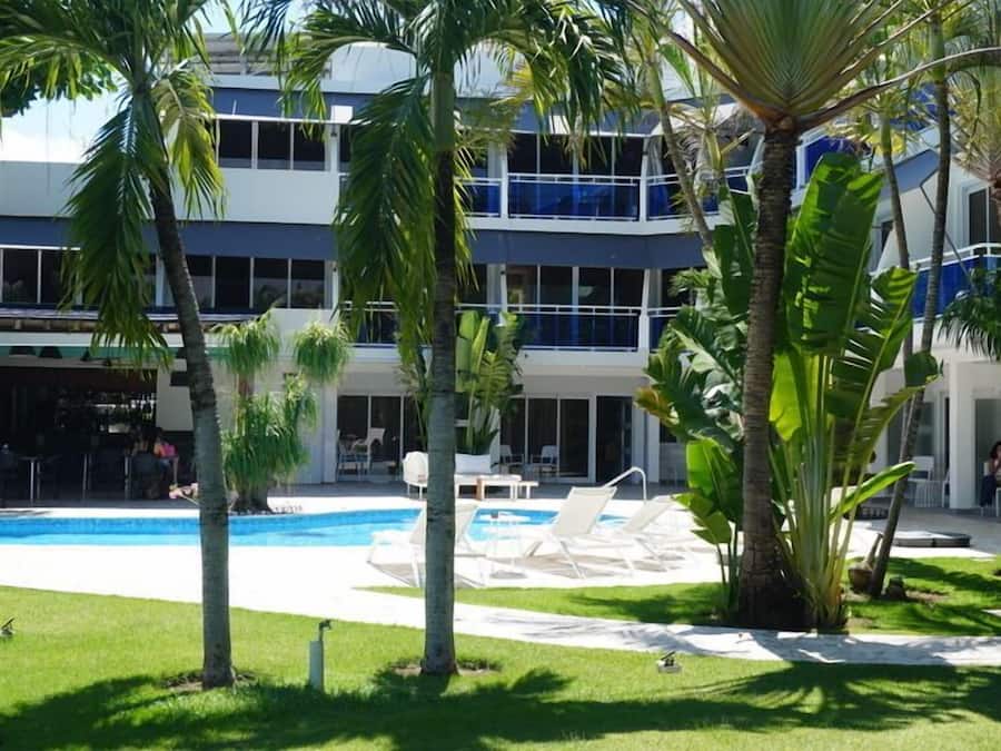 Un hotel con piscina, sillas de descanso y palmeras.