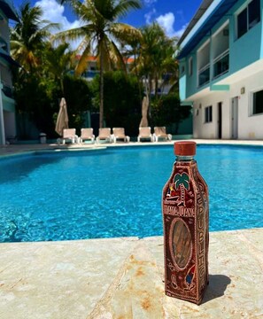 A bottle of Margaritaville Rum on a poolside with a clear blue pool and palm trees in the background. - New Garden Hotel (Sosúa)