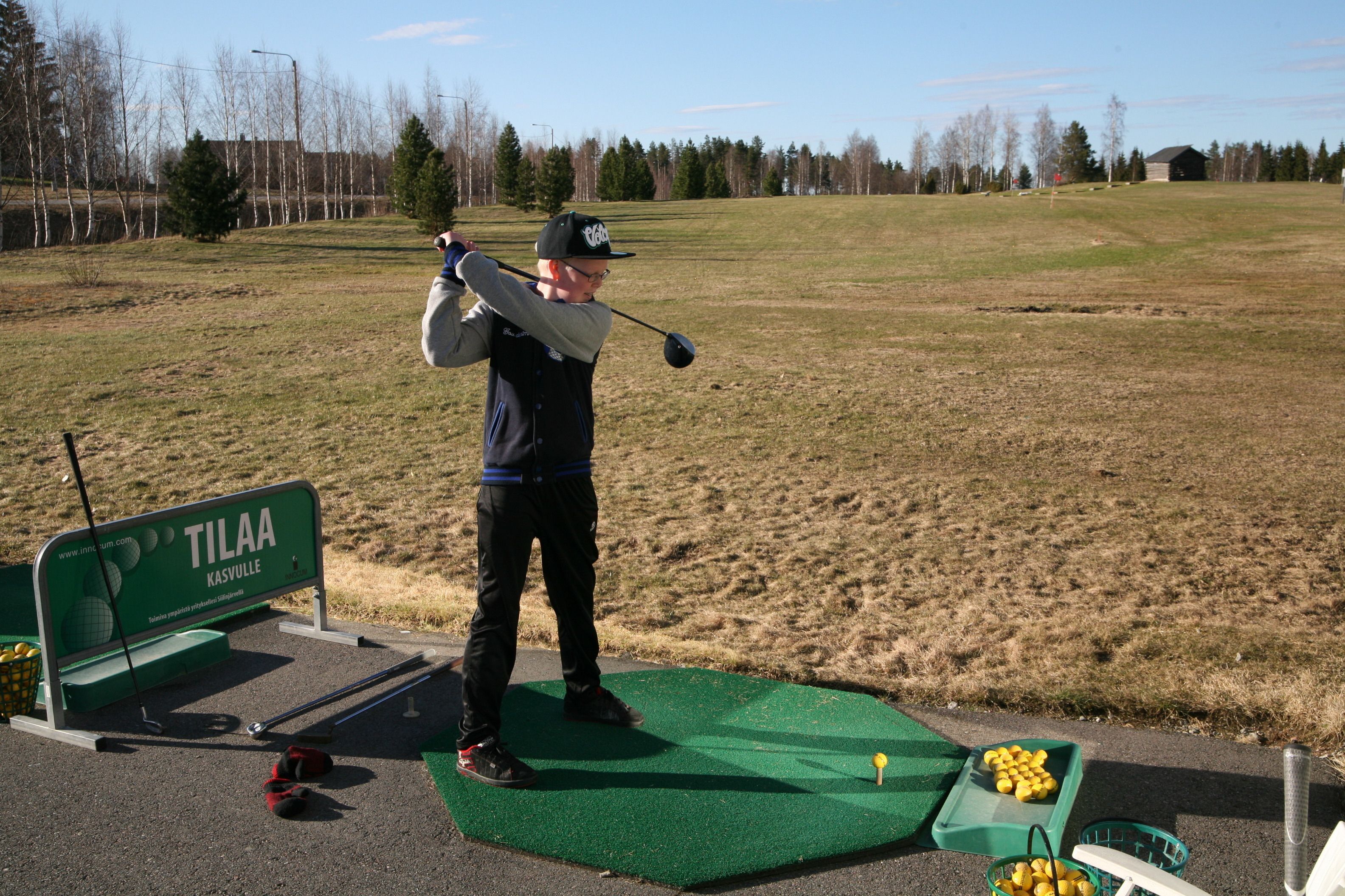 A golf course with a putting green, a golf bag, and a tee box.