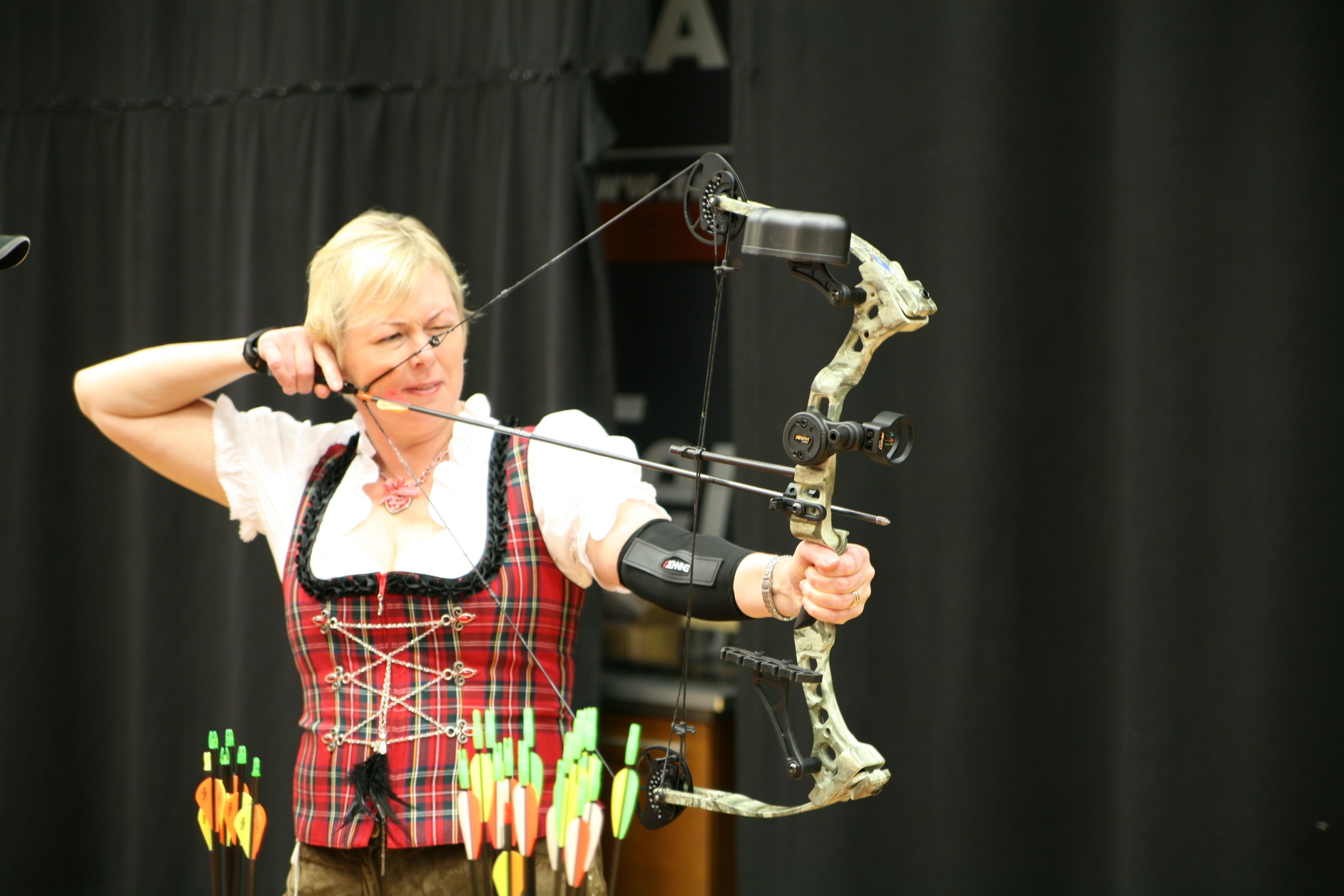 A person in traditional attire aiming a bow and arrow.