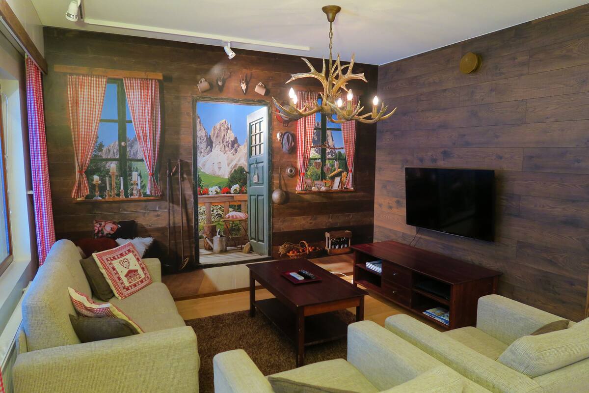 A living room with a sofa, a coffee table, a TV, and a wooden wall.
