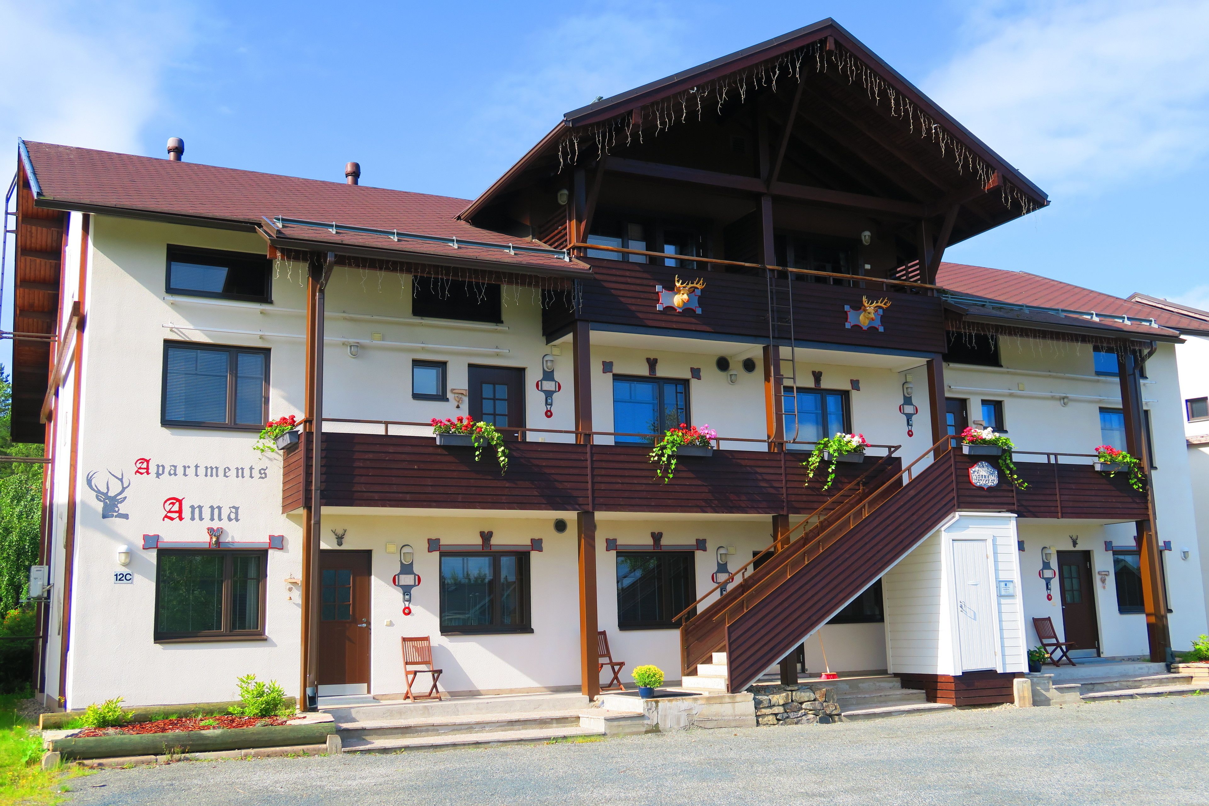 A multi-story building with a wooden facade, balconies with flower boxes, and a staircase leading to the upper levels.