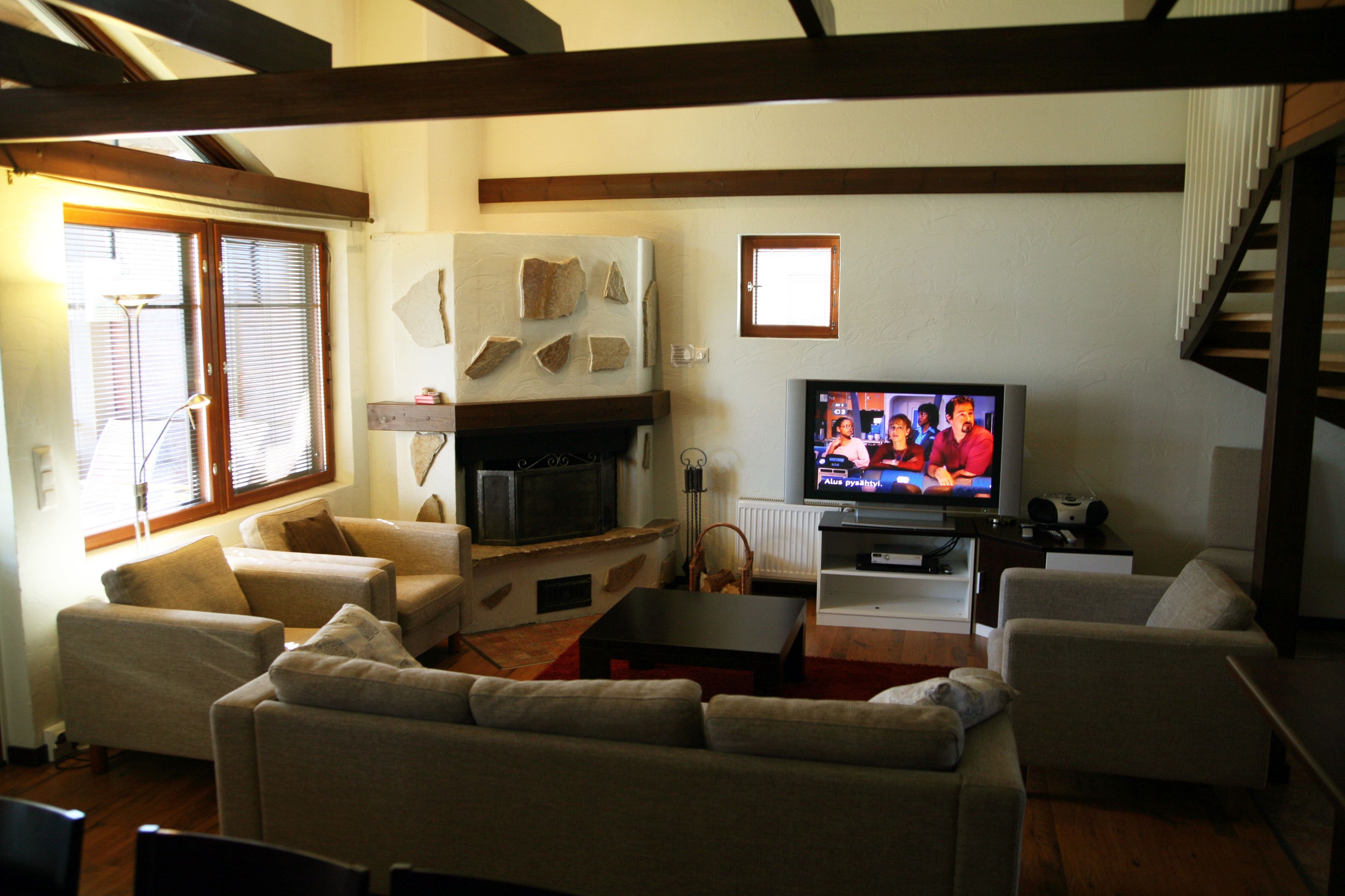 A living room with a fireplace, a television, and a staircase.