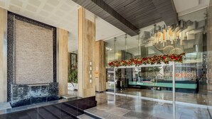 Un lobby moderno con pared de piedra, entrada de vidrio y una lámpara de araña.