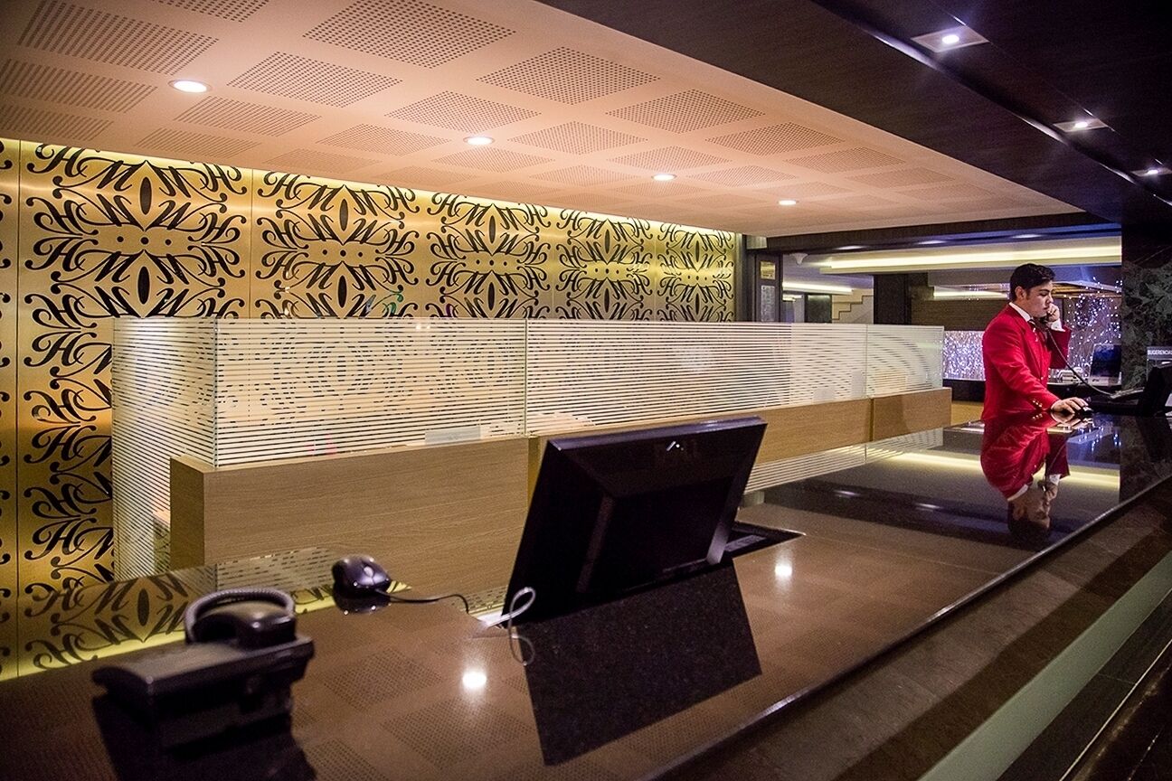 Un mostrador de recepción con un muro estampado, un monitor de computadora y un teléfono.