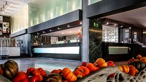 Un moderno vestíbulo de hotel con mostrador de recepción, una pared divisoria de vidrio y una decoración otoñal con calabazas.
