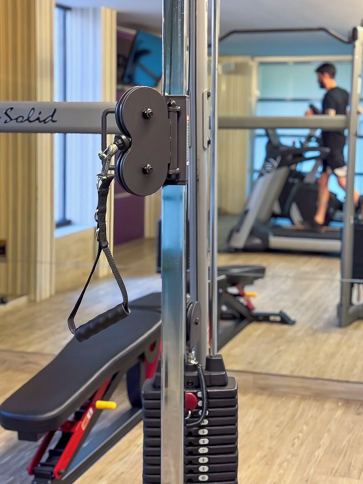 Un gimnasio con equipo de ejercicio, incluyendo una máquina de cables y una cinta de correr.