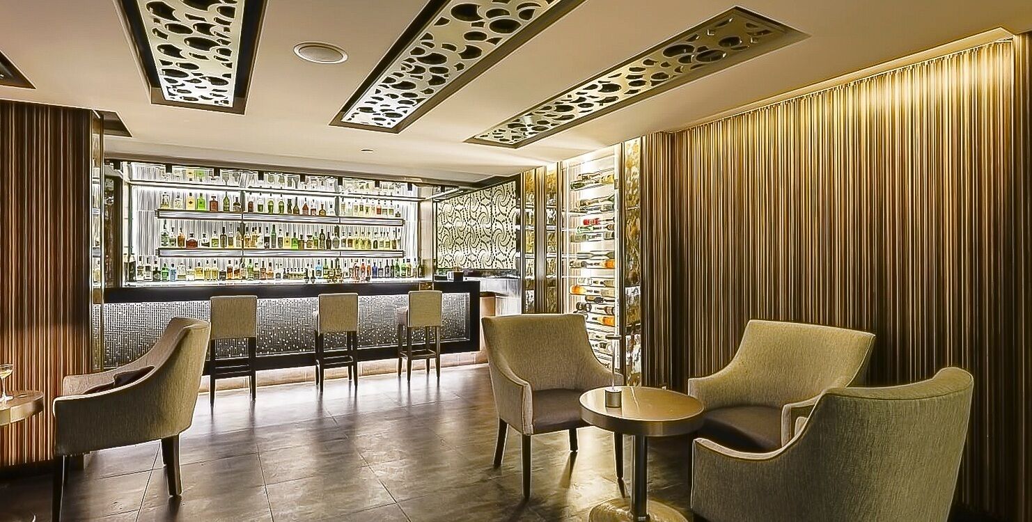 Eine Bar mit Bartresen, Flaschenregalen und Sitzgelegenheiten mit Stühlen und einem kleinen Tisch.