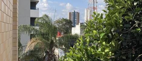 Un edificio de varios pisos, rodeado de vegetación y un cielo despejado.