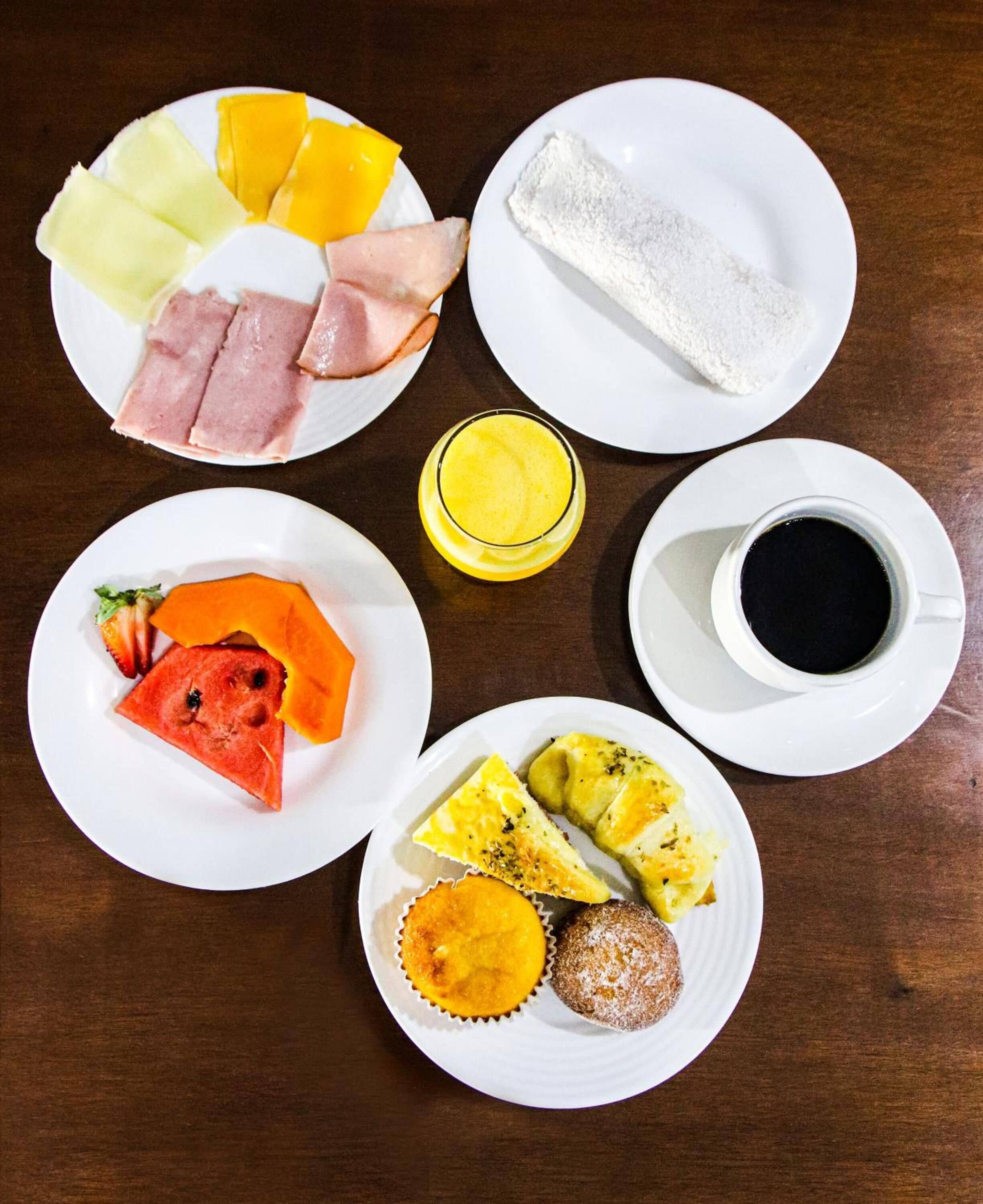 Una colazione con piatti di frutta, dolci e una tazza di caffè.
