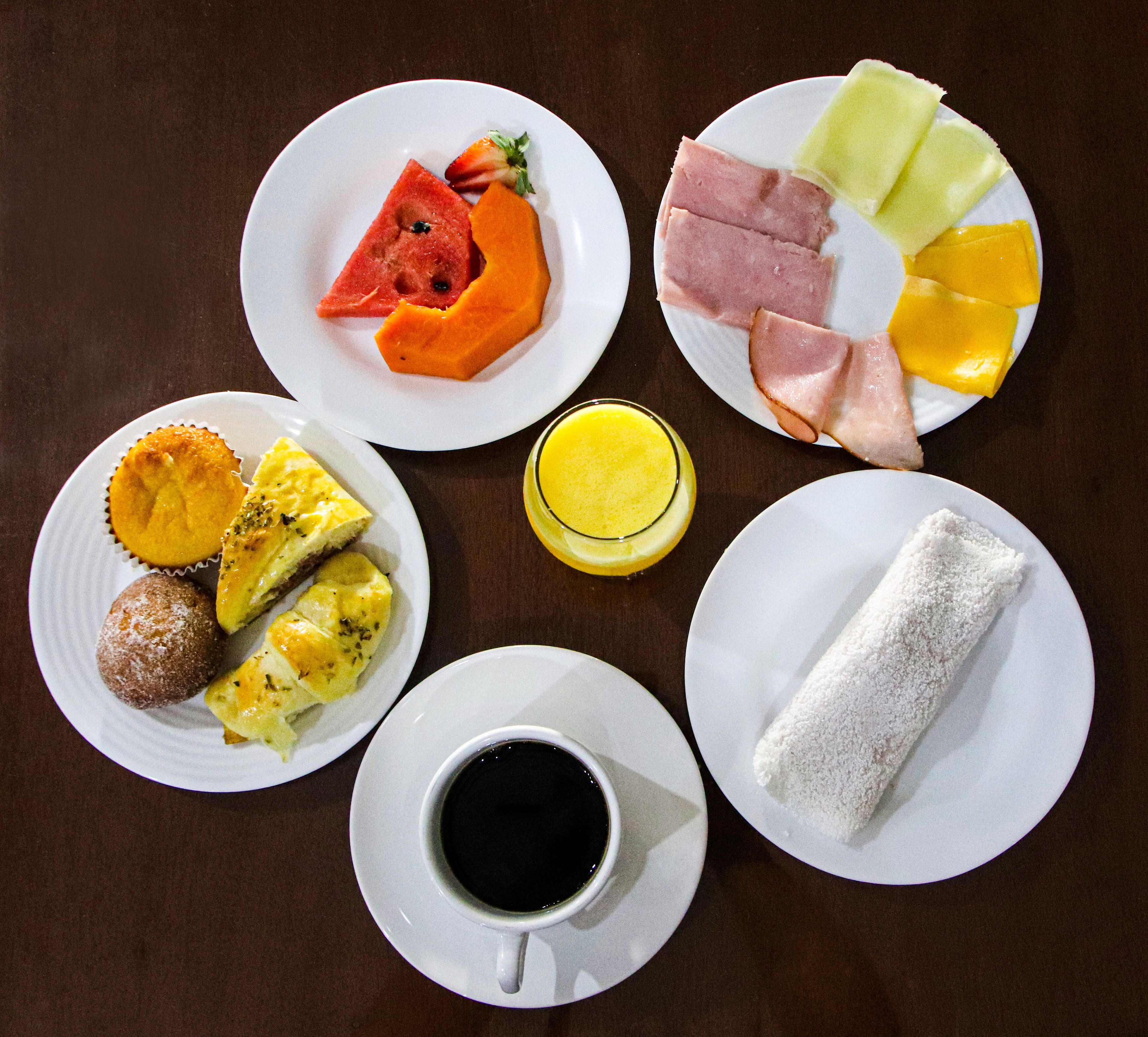 A breakfast table with plates of food, including eggs, ham, fruit, and a cup of coffee.