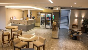 Un vestíbulo con mostrador de recepción, zona de estar y un refrigerador lleno de bebidas.