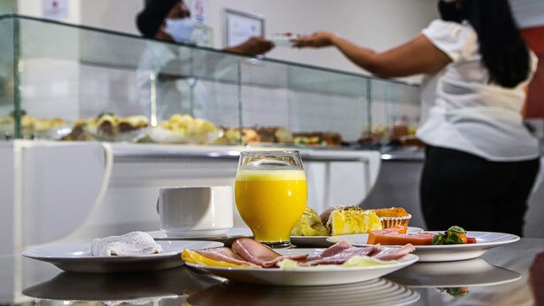 Un bufé de desayuno con diversos platos y un vaso de zumo de naranja en una mesa.