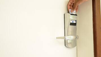 A hand inserting a card into a modern, metallic door lock.
