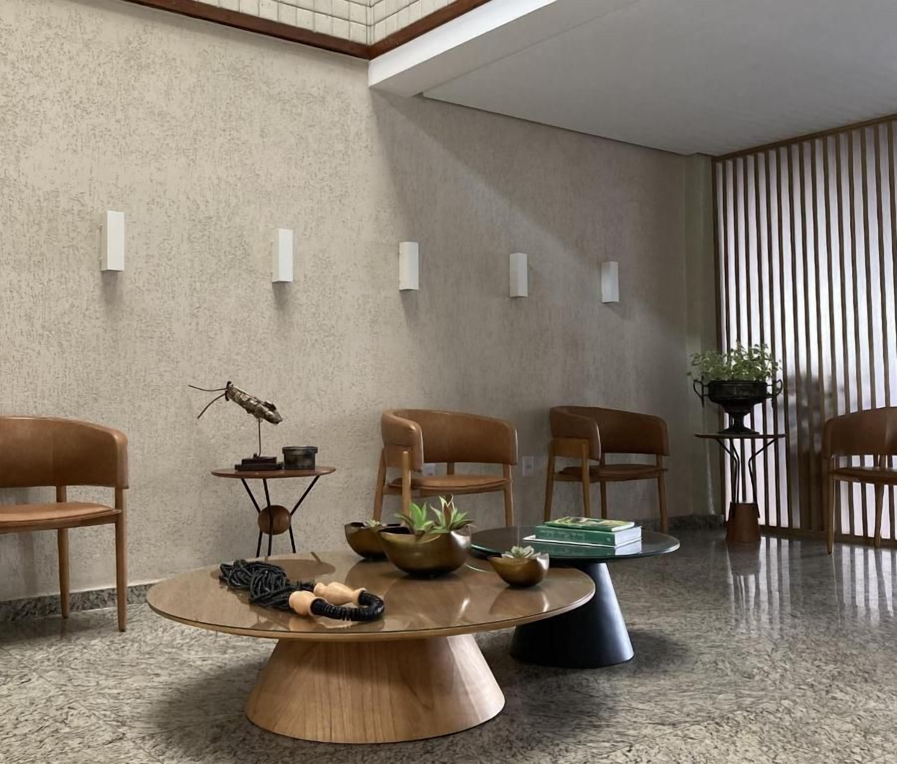 Un vestíbulo moderno con una mesa redonda de madera, varias sillas, una escultura decorativa de un insecto y una cortina a rayas.