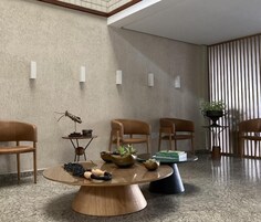 Un vestíbulo moderno con una mesa redonda de madera, varias sillas, una escultura decorativa de un insecto y una cortina a rayas.