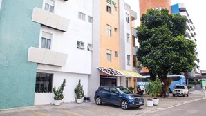 Un hotel de diseño moderno, con fachadas que combinan blanco y naranja, una entrada destacada con toldo amarillo y un gran árbol al frente.