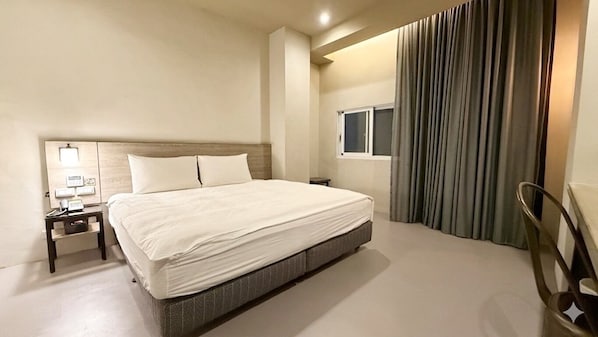 A hotel room with a large bed, a nightstand with a lamp, a window, and a curtain. - Kiwi Express Hotel - Taichung Station Branch II (Taichung)