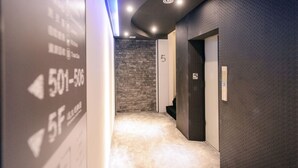 Un pasillo con una pared con textura, suelo alfombrado y una puerta que indica '5F'.
