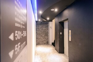Un pasillo con una pared con textura, suelo alfombrado y una puerta que indica '5F'.
