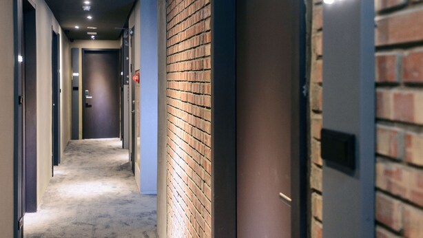 Un pasillo con una pared de ladrillo a un lado y una puerta al otro.