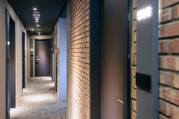 Un pasillo con una pared de ladrillo a un lado y una puerta al otro.