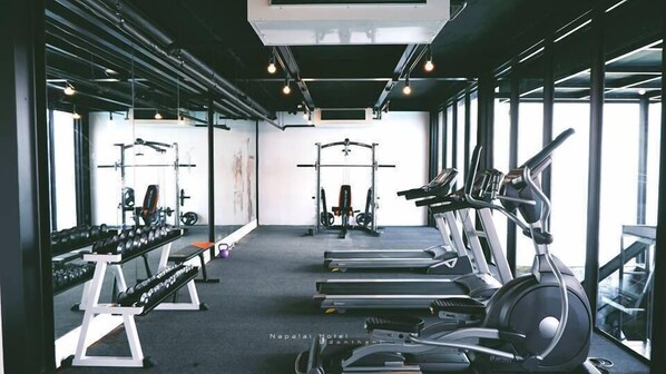 Un gimnasio con cintas de correr, máquinas de pesas y mancuernas.