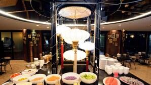 A buffet setup with various food items and a central decorative light fixture. - Napalai Hotel (Udon Thani)