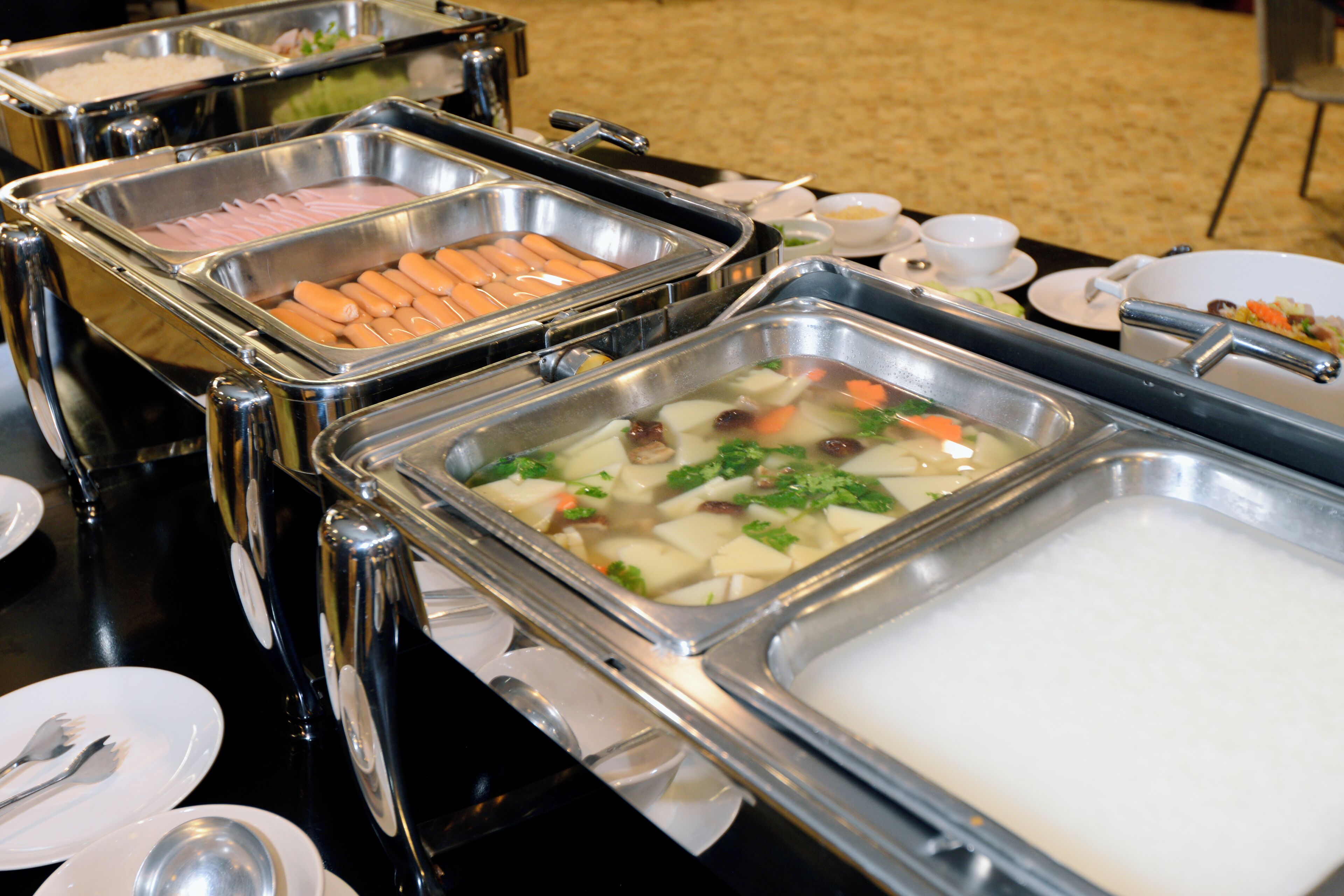 Buffet amb diverses opcions gastronòmiques, com ara hot dogs, verdures i arròs.