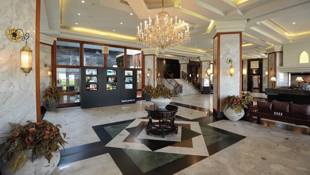 A lobby with a chandelier, reception desk, and a staircase. - Napalai Hotel (Udon Thani)