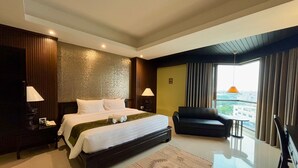 A modern hotel room with a large bed, a sofa, a view of the city, and a balcony. - Napalai Hotel (Udon Thani)