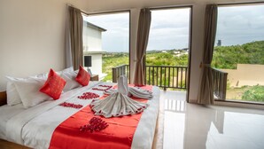 Een ruime slaapkamer met een groot bed, een balkon met uitzicht op groen, en een modern interieur.