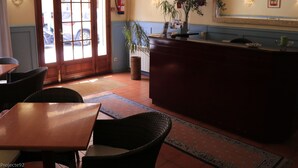 A hotel lobby with a reception desk, seating area, and a fire extinguisher on the wall. - Hotel Torino (Masnou)