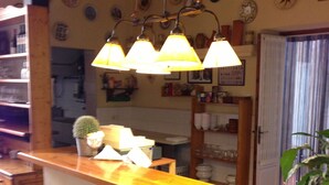 A kitchen with a wooden bar, two stools, hanging pendant lights, and various kitchen items. - Hotel Torino (Masnou)