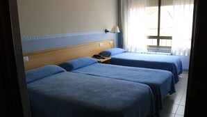 A hotel room with two single beds, a nightstand with a phone, and a window with curtains. - Hotel Torino (Masnou)